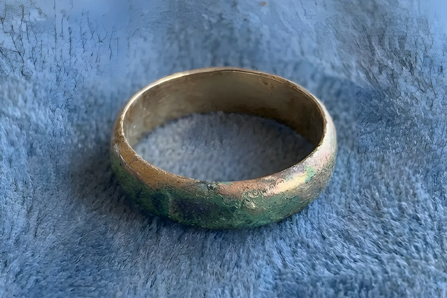 A gold-plated band with green corrosion spreading along the outside where the plating has worn through to the brass.