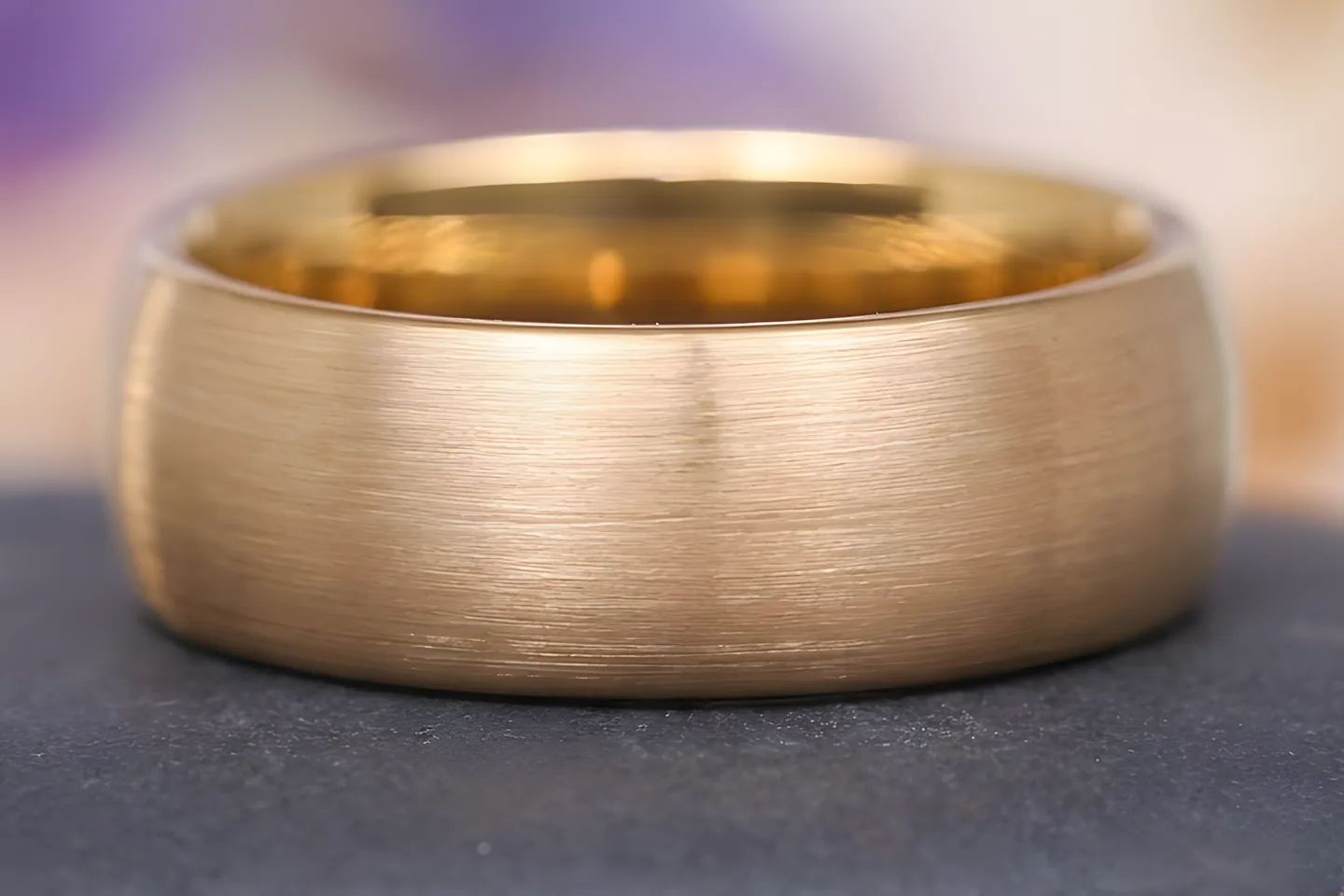 Macro of a brushed solid gold band. The colour runs through the metal rather than sitting on the surface.