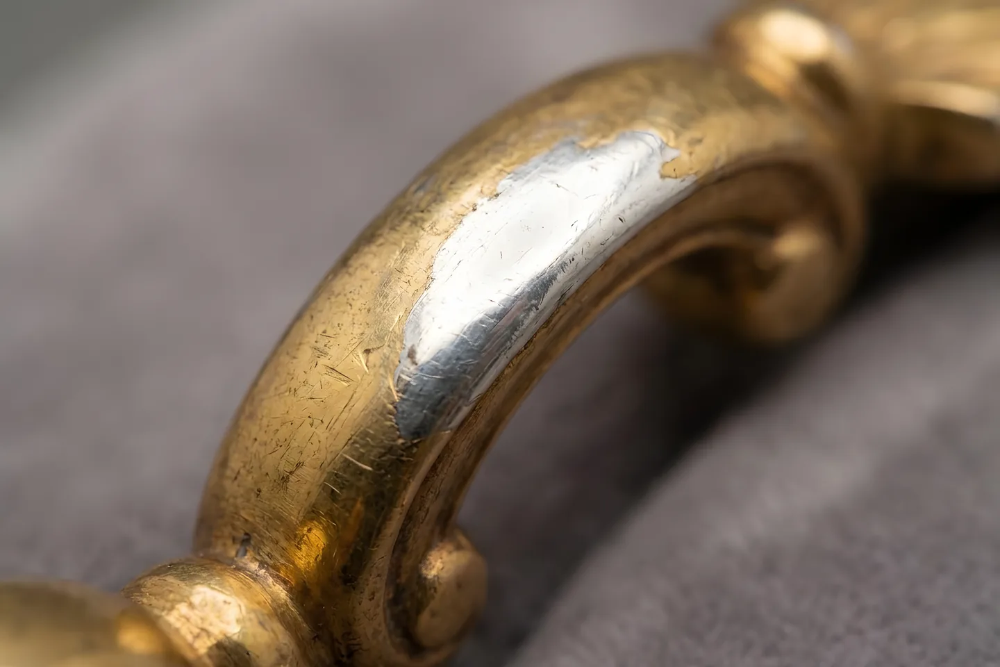 A gold-covered link worn through at the high point, showing the sterling silver underneath.